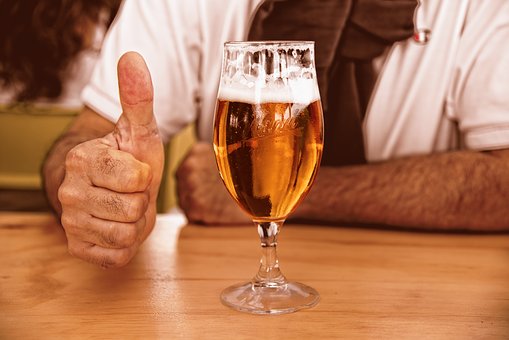 Uomo che beve birra e mostra pollice alzato